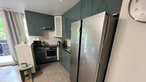 A compact kitchen with a stainless steel refrigerator, a microwave, and a stove. - Bright and Spacious 3-Bedroom Apartment - Direct Access to Central Paris (Choisy-le-Roi)