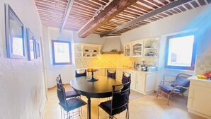 A kitchen with a round table and chairs, white cabinets, and a tiled floor.