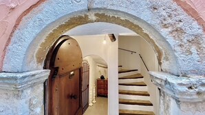 An arched doorway leading to a staircase with a wooden door on the left.