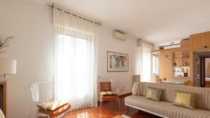 A living room with a sofa, chairs, a coffee table, and a painting on the wall.