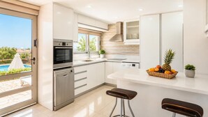 Een moderne keuken met roestvrijstalen apparatuur, een groot raam en uitzicht op een zwembad.