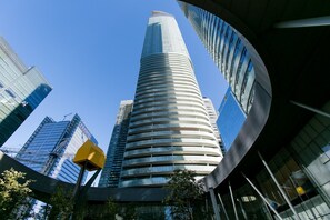 A modern skyscraper with a curved facade and reflective glass windows. - Bright 2 BR Condo - Jays, MTCC, CN Tower (Toronto)