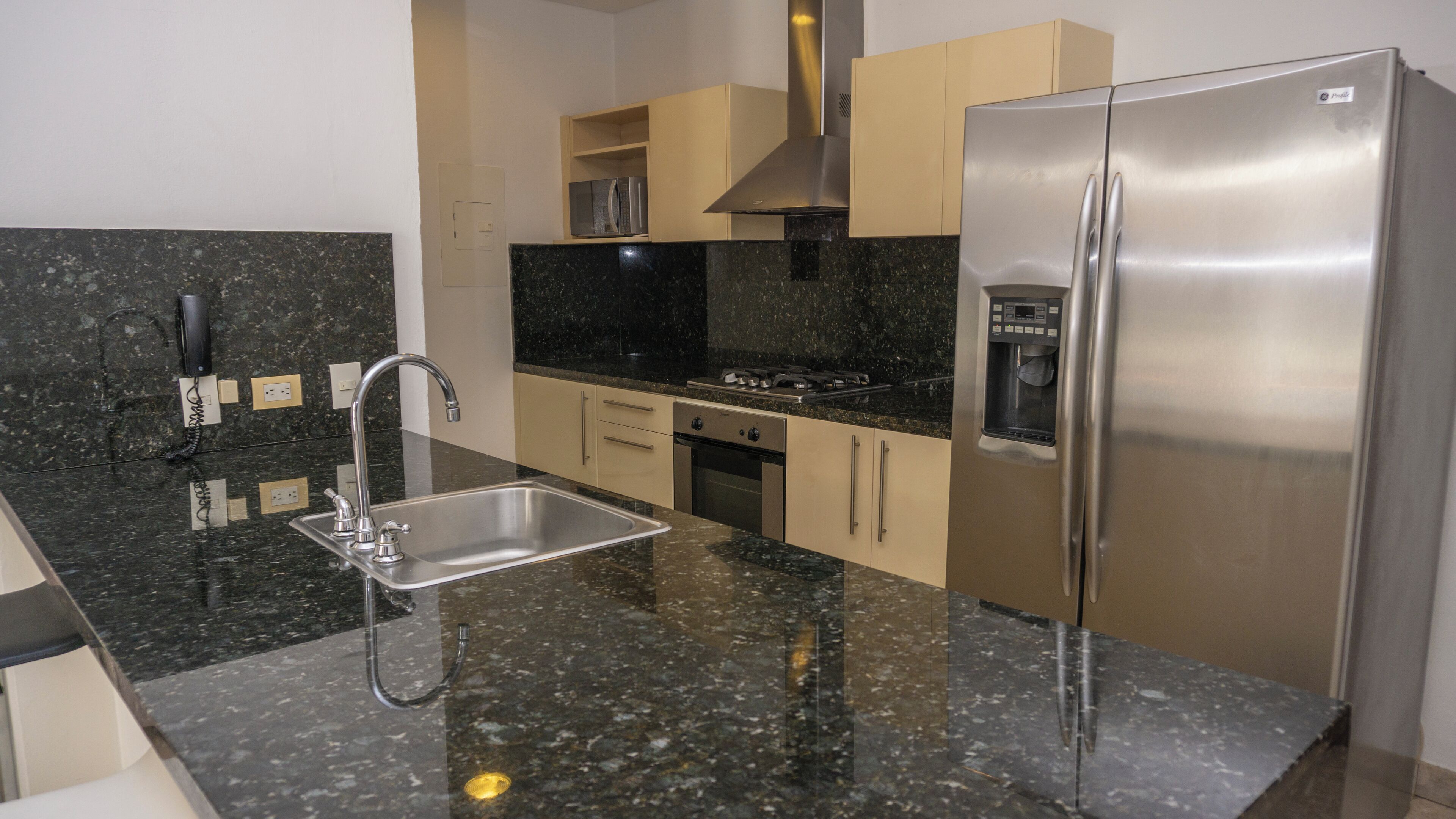 A modern kitchen with a stainless steel refrigerator, a built-in oven, a gas stove, and a sink with a faucet.