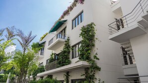 A multi-story building with balconies, some with plants and flowers.