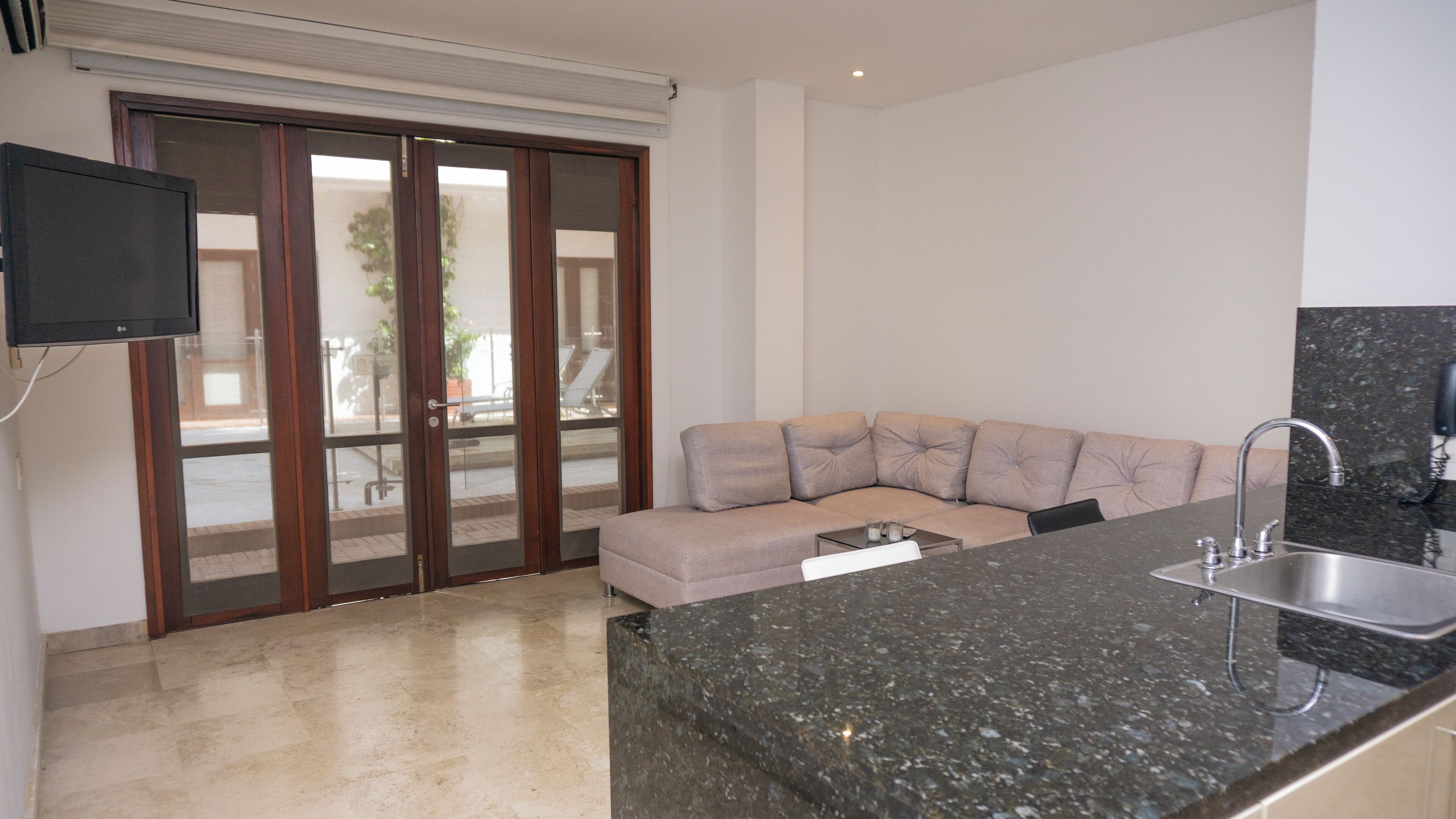 A modern kitchen with a granite countertop, a built-in sink, and a beige sofa.
