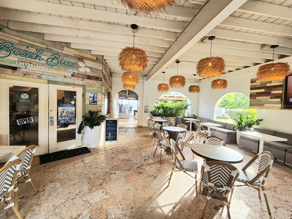 A beach-themed cafe with a wooden facade, outdoor seating, and hanging light fixtures.