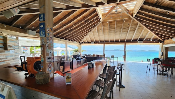 A wooden bar area with a view of the sea, a sign prohibiting smoking, and a sign for room rentals.
