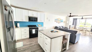 A modern kitchen with white cabinets, a stainless steel refrigerator, and a microwave.