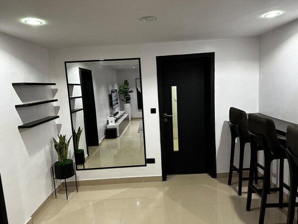 A modern interior with a mirrored wall, a black door, and a seating area with two chairs.
