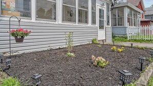 A house with a garden bed, hanging flower pots, and outdoor lanterns. - Stylish 2BR Syracuse Stay, Near Zoo, Museums and Downtown (Syracuse)