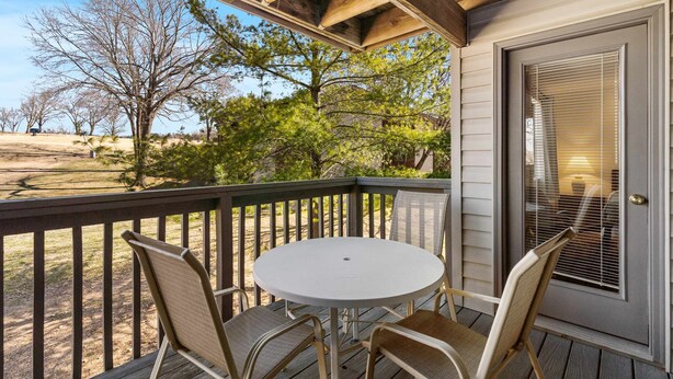 A covered outdoor seating area with a table and chairs, overlooking a natural landscape.