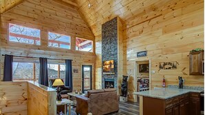 Un intérieur spacieux de chalet en bois, avec une cheminée, des murs en bois et un coin repas.