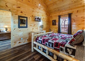 A wooden cabin bedroom with a bed, a nightstand, and a dresser.