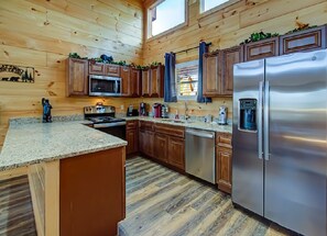 A modern kitchen with wooden cabinets, stainless steel appliances, granite countertops, and a large island.