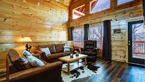 Un intérieur de chalet chaleureux, avec un revêtement mural en bois, un canapé en cuir, une table basse et un tapis en peau de vache.