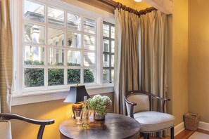A room with a large window, a table with a lamp, chairs, and a small plant. - Cedar Mansion Estate & Bungalows - London Suite (Sonoma)