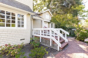 A house with a white exterior, a front porch with a white railing, and a brick pathway leading to the entrance. - Cedar Mansion Estate & Bungalows - London Suite (Sonoma)