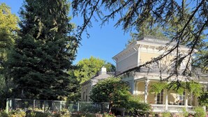 A large, historic house with a spacious lawn and a fenced garden area.