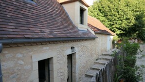 A stone building with a tiled roof, a small window, and a wooden fence.