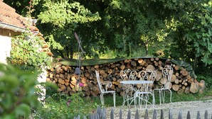 A garden with a metal table and chairs, a wooden fence, and a stack of firewood.