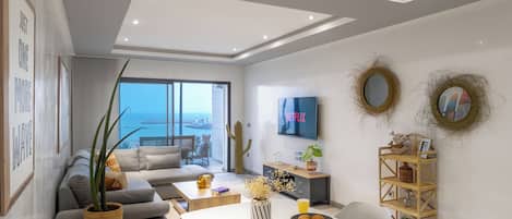 Un salon moderne avec un canapé, une table basse et un téléviseur fixé au mur.