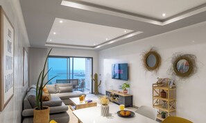 A modern living room with a sofa, coffee table, and a TV mounted on the wall. - Stayhere - Agadir - Marina Residential Living (Inezgane)