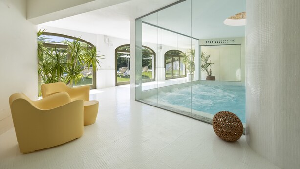 Een modern interieur met een glazen wand, een zwembad en gele stoelen.