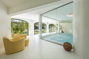 Un intérieur moderne avec un mur de verre, une piscine et des chaises jaunes.