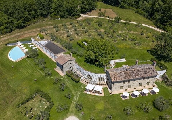 An aerial view of a large estate with a swimming pool, multiple buildings, and extensive landscaping.
