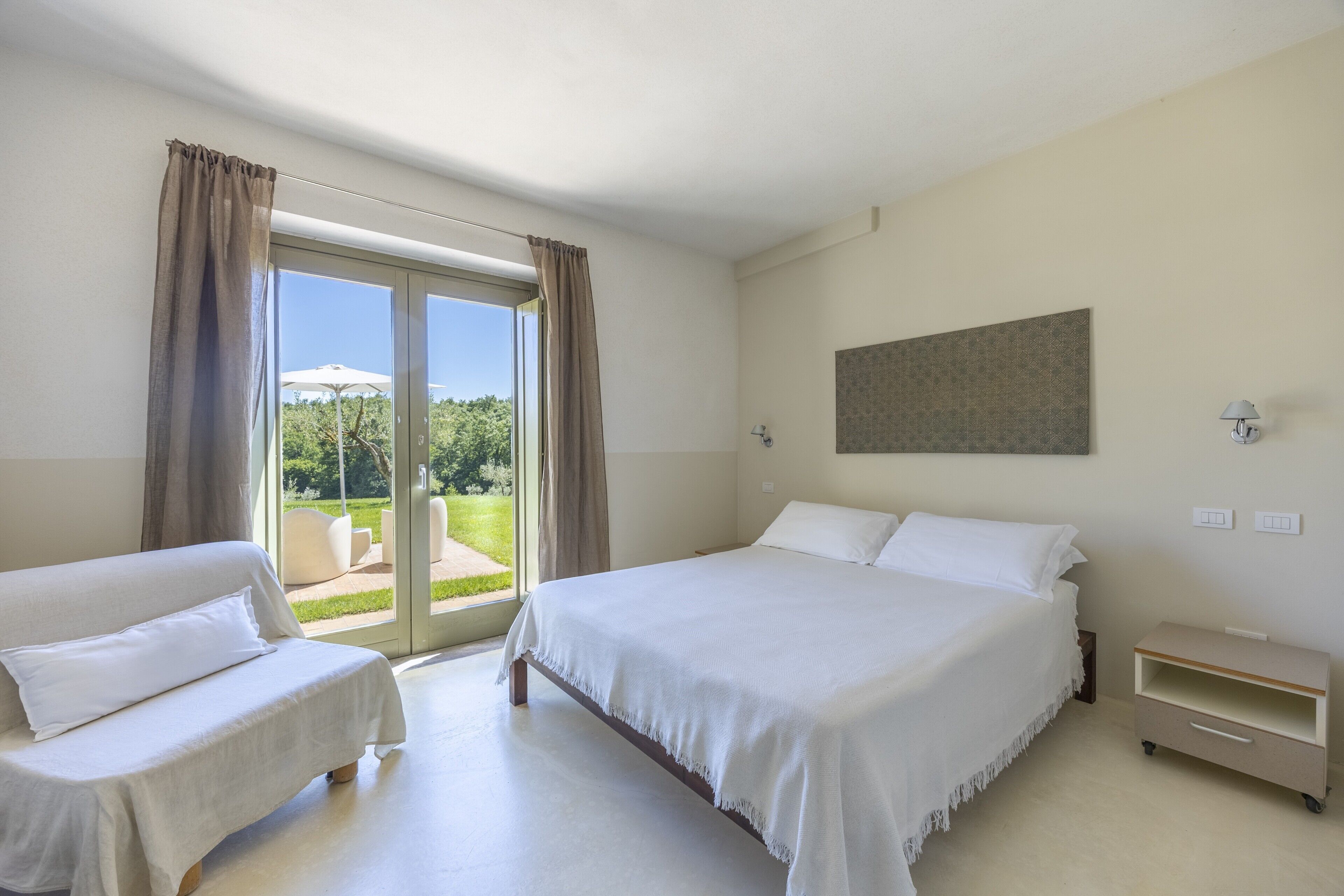 Habitación de hotel con cama, sofá, una mesita y vistas al exterior.
