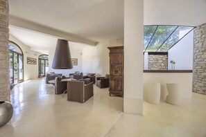 A spacious room with a stone wall, a wooden cabinet, and a large hanging light fixture.