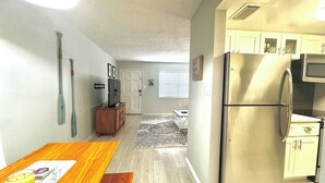 Una cocina funcional con refrigerador, microondas y mesa de comedor de madera.