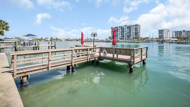 Un muelle de madera se extiende sobre aguas tranquilas, con un flotador anclado a la barandilla.