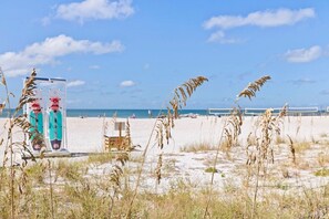 A beach with lifeguard towers, a volleyball net, and tall grasses.