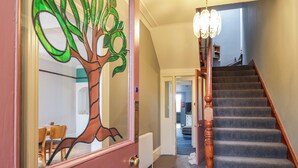 A staircase with a wooden handrail and a chandelier. - Crannoch Self Catering (Buckie)