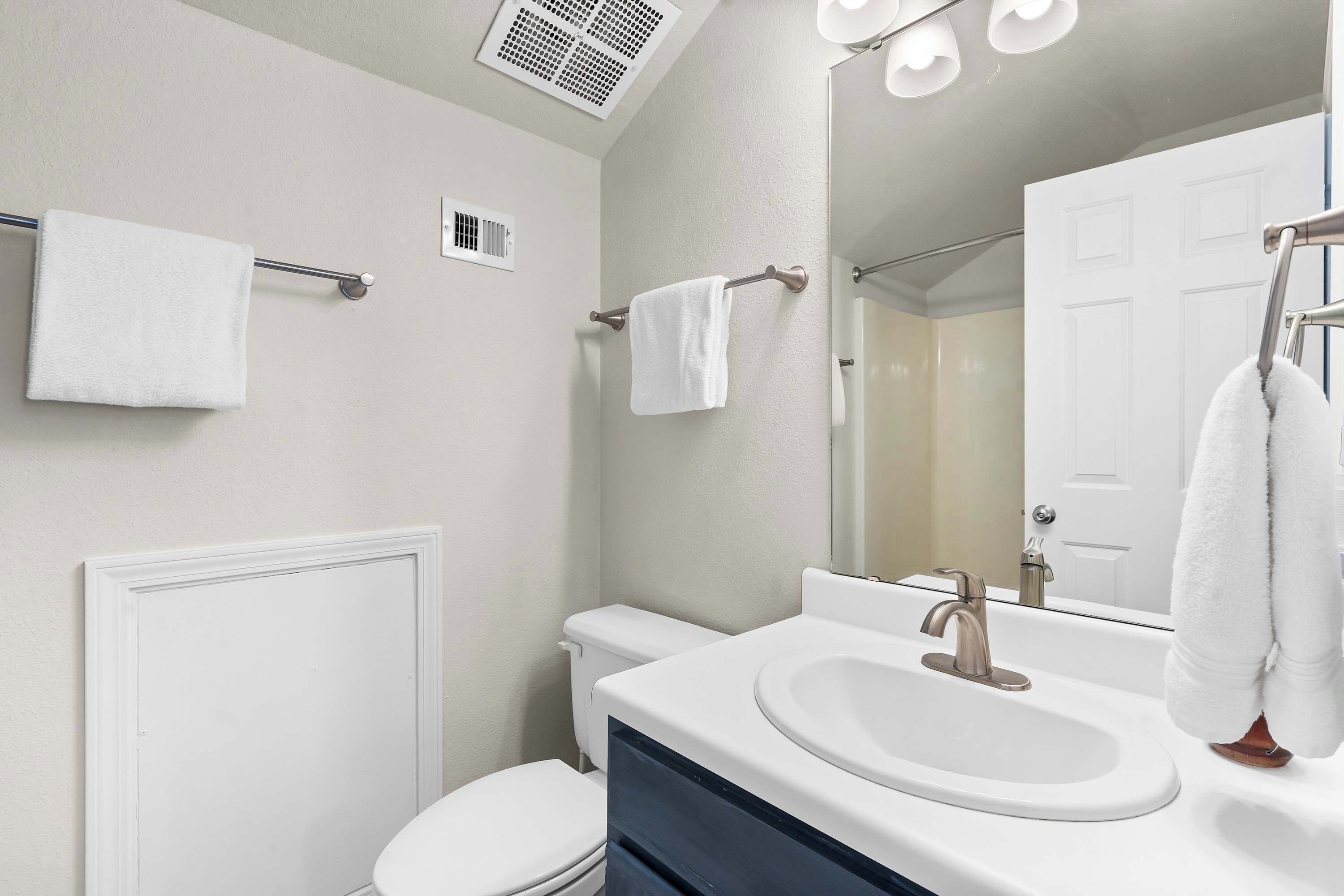 Een moderne badkamer met een wit wastafelmeubel, een toilet en een spiegel.