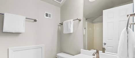 Een moderne badkamer met een wit wastafelmeubel, een toilet en een spiegel.