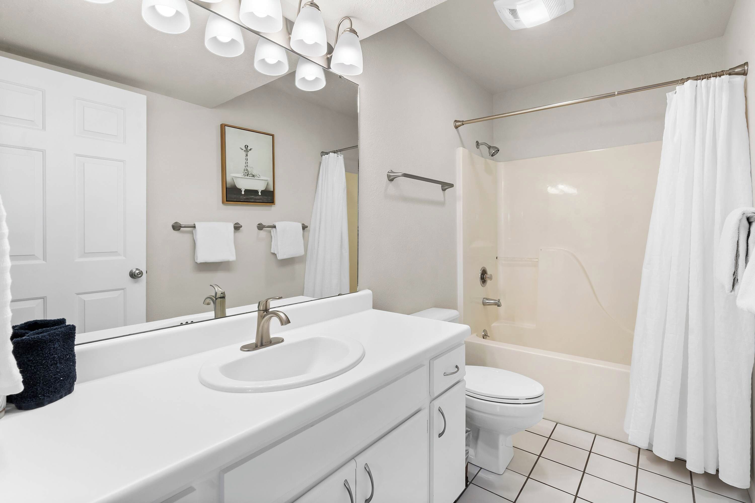 Une salle de bain moderne avec un grand miroir, un lavabo blanc et une douche à parois de verre.