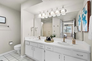 A modern bathroom with a white vanity, two sinks, a large mirror, and a shower area. - The Joyful Getaway For 8! (Branson)