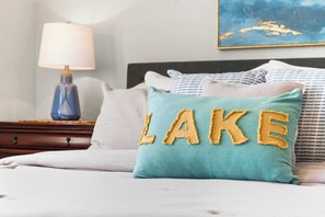 A bed with a teal pillow featuring the word "LAKE" embroidered in yellow. - The Joyful Getaway For 8! (Branson)