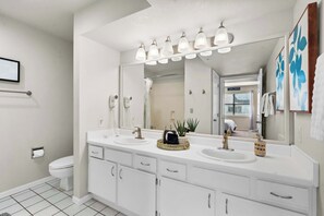 A modern bathroom with a white vanity, two sinks, a large mirror, and a shower area. - The Joyful Getaway For 8! (Branson)