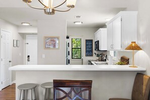 A modern kitchen with white cabinetry, a central island, and bar stools. - The Joyful Getaway For 8! (Branson)