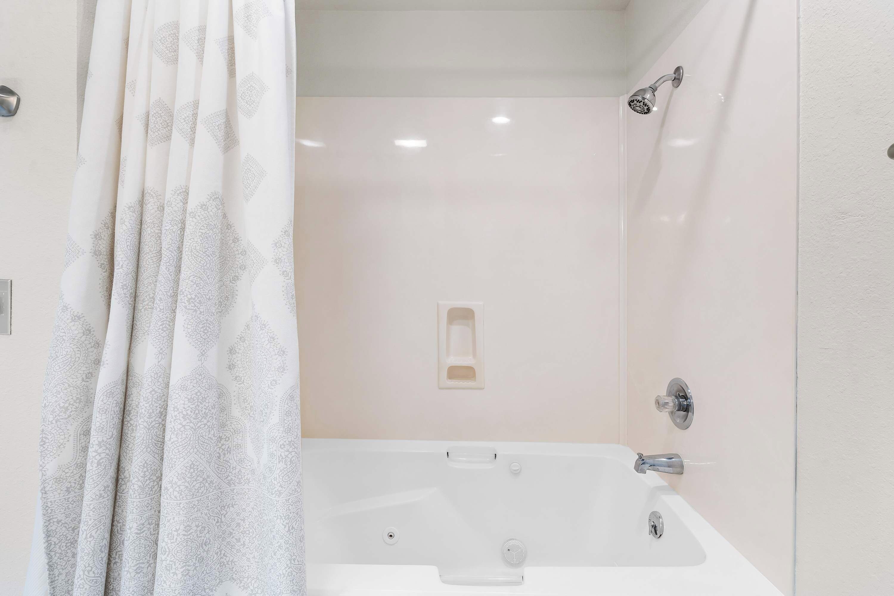 Une salle de bain avec une baignoire blanche, une pomme de douche et un porte-serviettes.