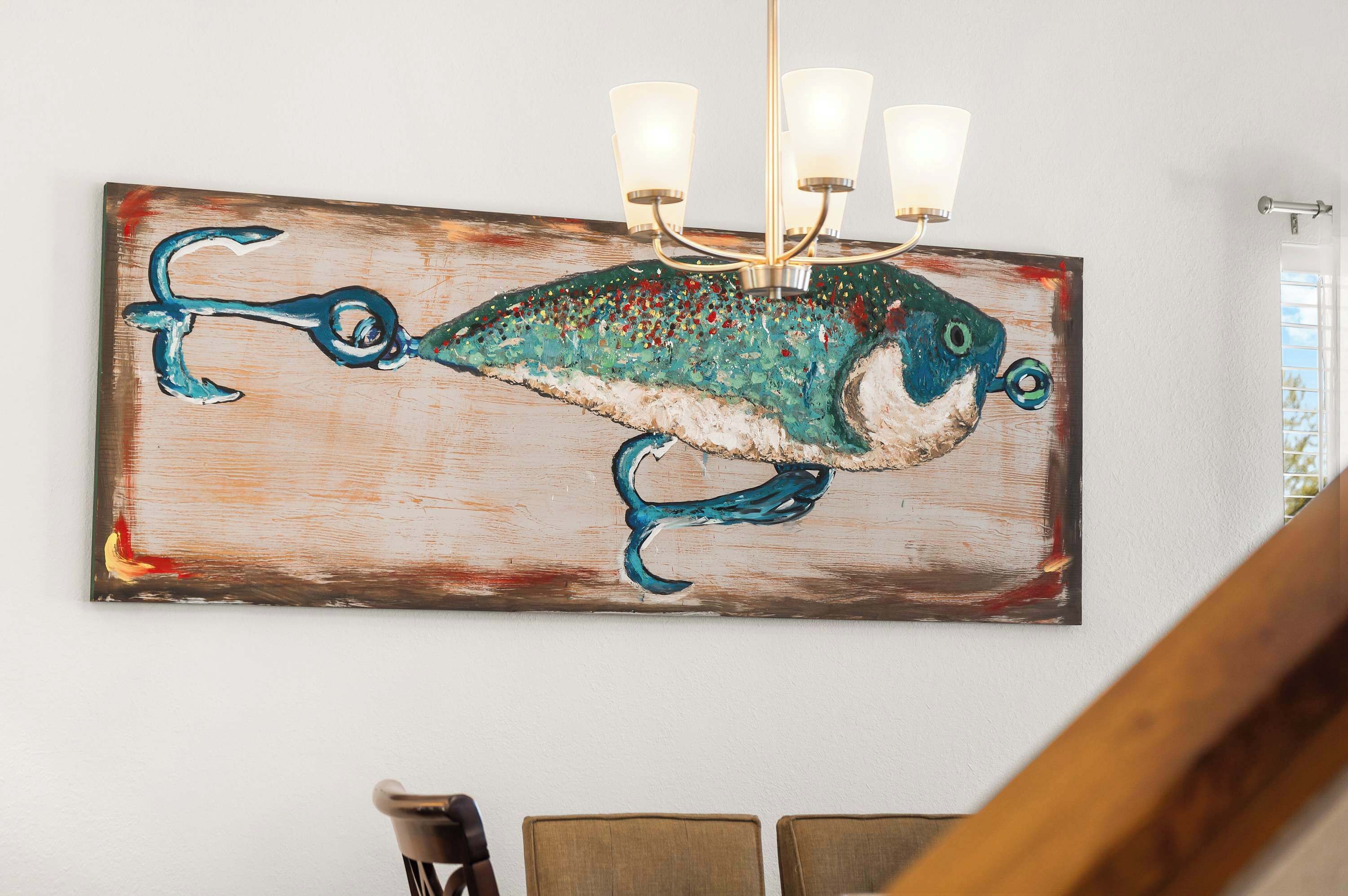 Ein Wandbild mit einem Fisch, eine Chandelüster und eine Treppe.