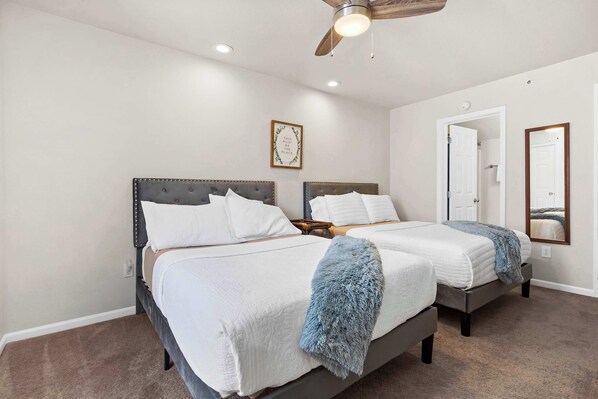 A bedroom with two beds, a ceiling fan, and a mirror on the wall. - The Joyful Getaway For 8! (Branson)