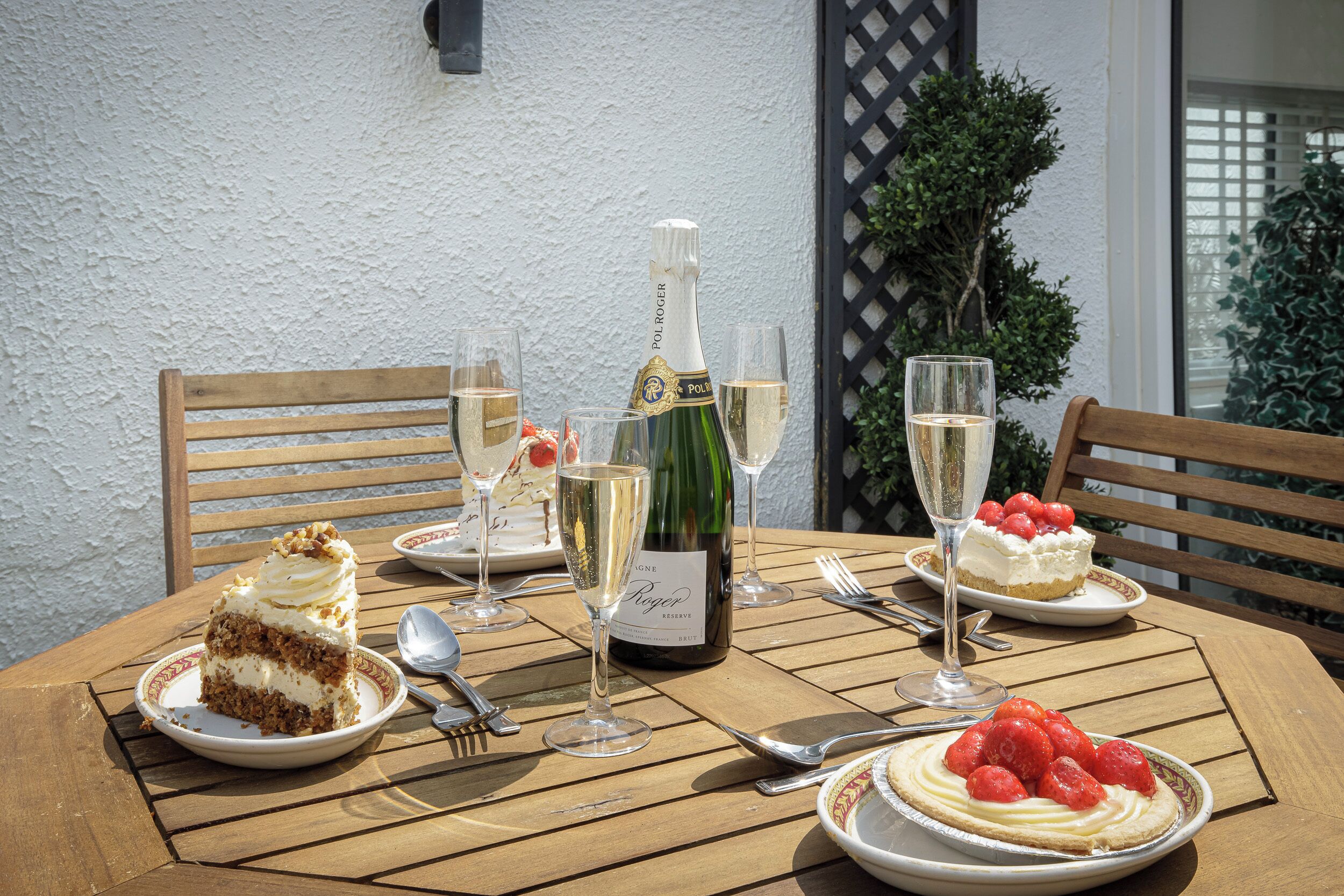 Een houten tafel gedekt met taartborden, champagneglazen en bestek.