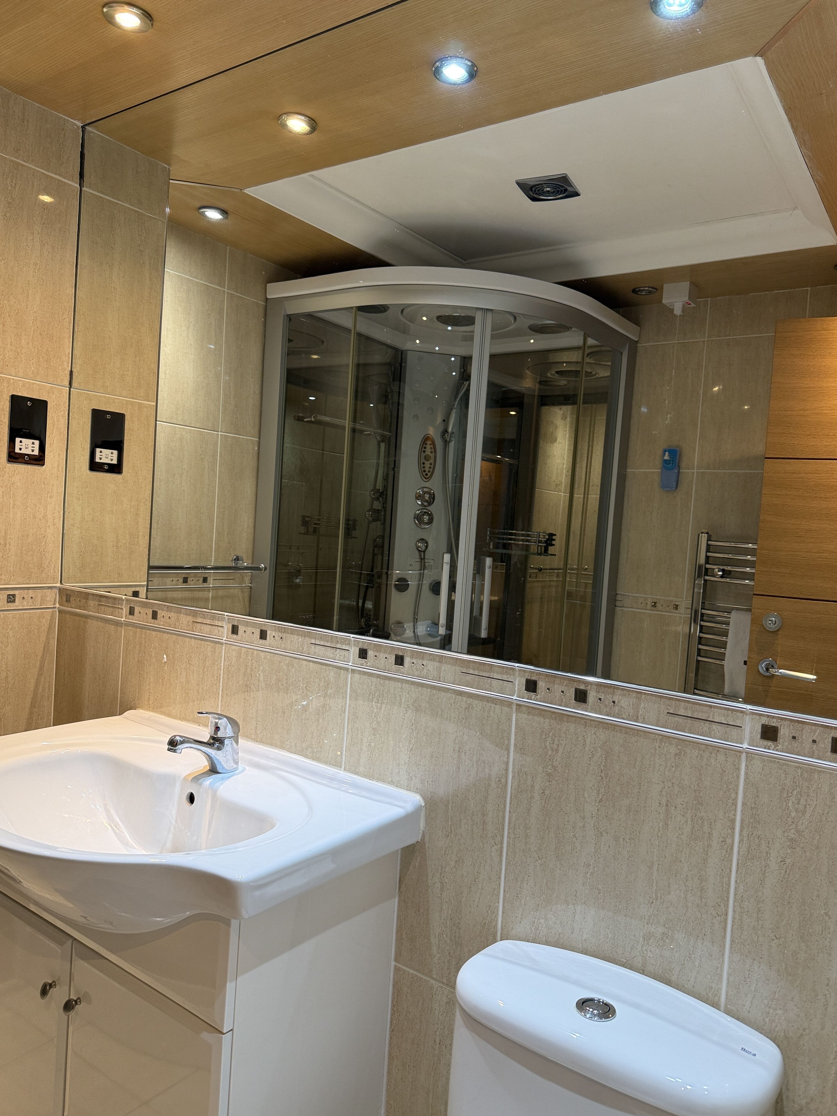 A modern bathroom with a white sink, a toilet, and a glass-enclosed shower.