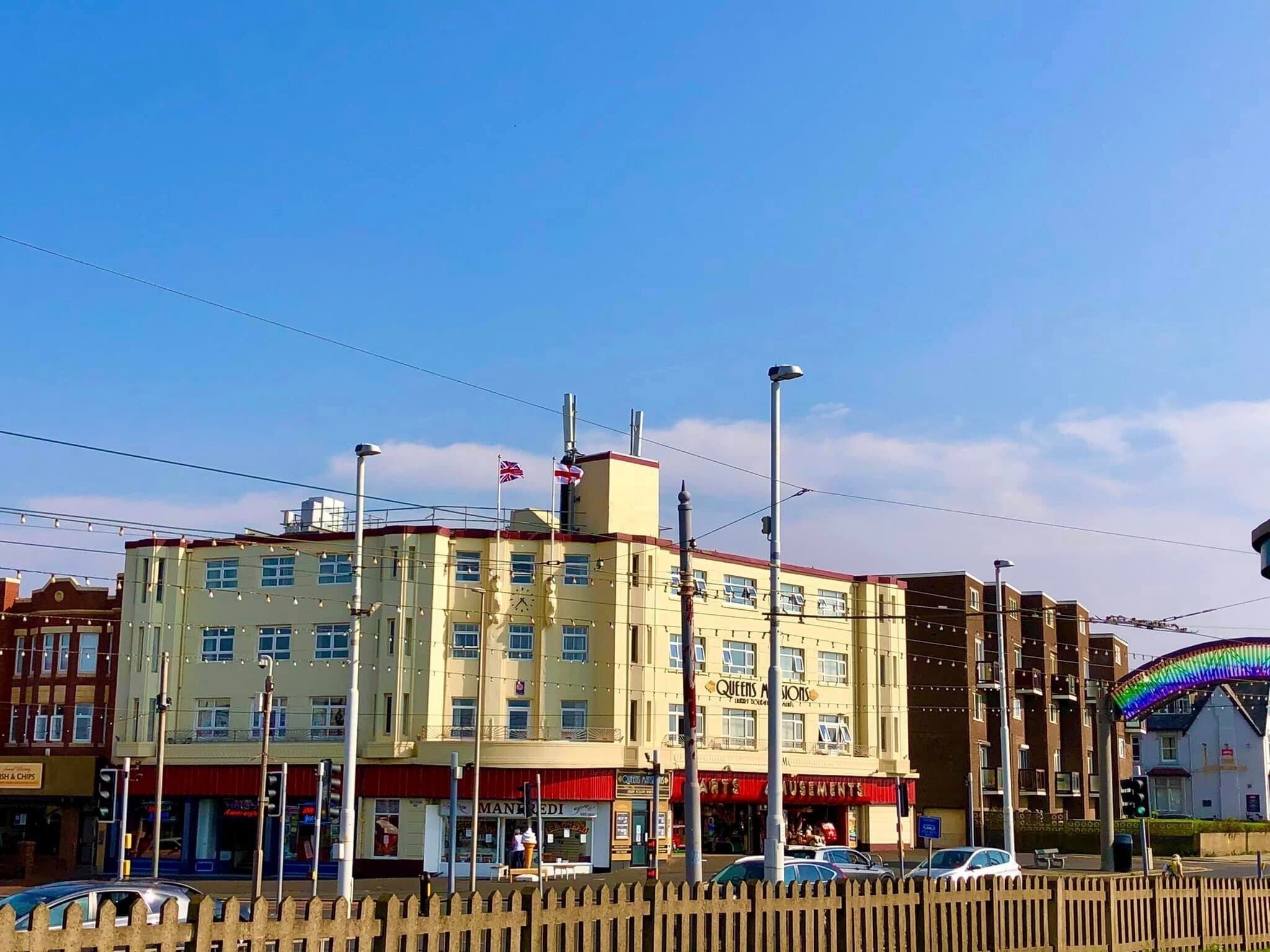 A multi-story building with a ground floor featuring a shop named "Queens & Monks."