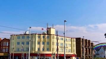 A multi-story building with a ground floor featuring a shop named "Queens & Monks."