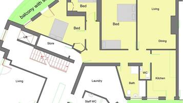 Et hotel layout med balkon og havudsigt, terrasse, flere soveværelser, spiseområde, opholdsstue, køkken, badeværelse, vaskerum og personaletoilet.